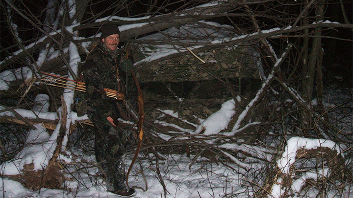 Traditional recurve bowhunter walking to ground blind in the snow