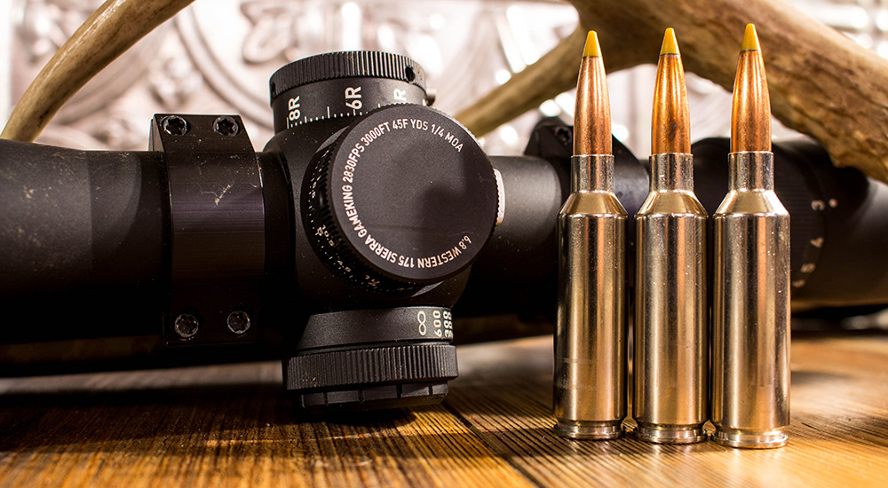 Three 6.8 Western ammunition cartridges next to Leupold rifle scope.