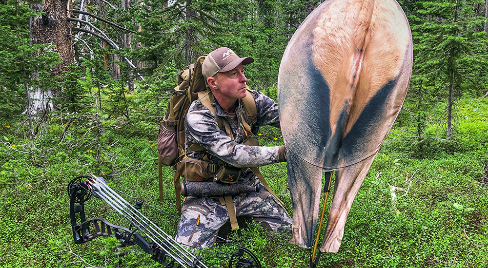 Hunter placing cow elk decoy in ground.