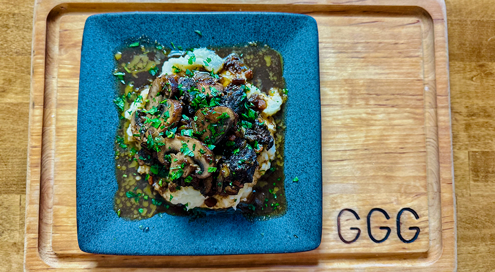 Venison Bourguignon plated on wood cutting board.