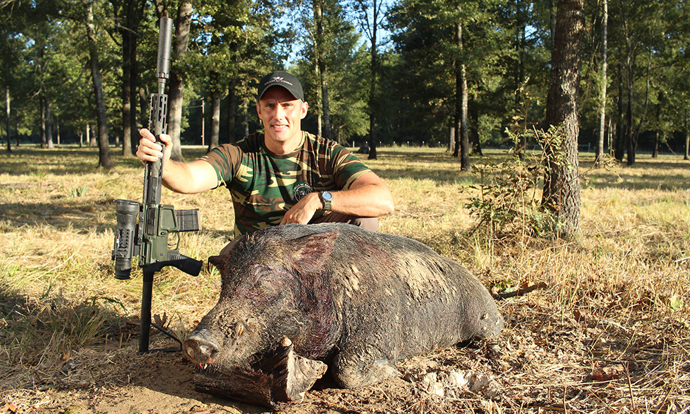 Hunter posing with feral hog while holding Wilson Combat .300 HAM