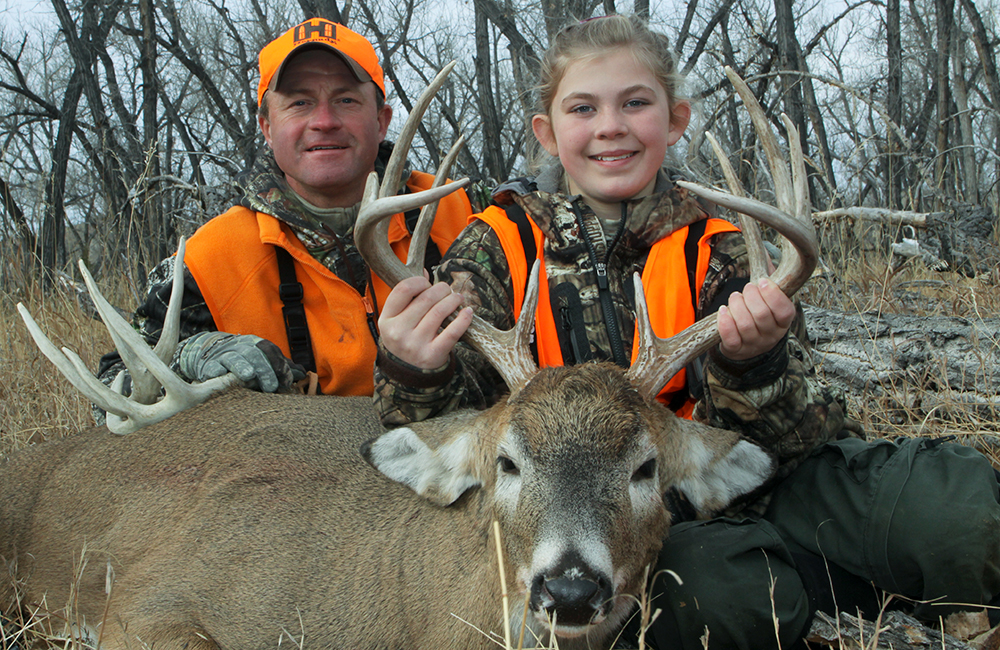 Male and young female hunter posing with whitetail deer.