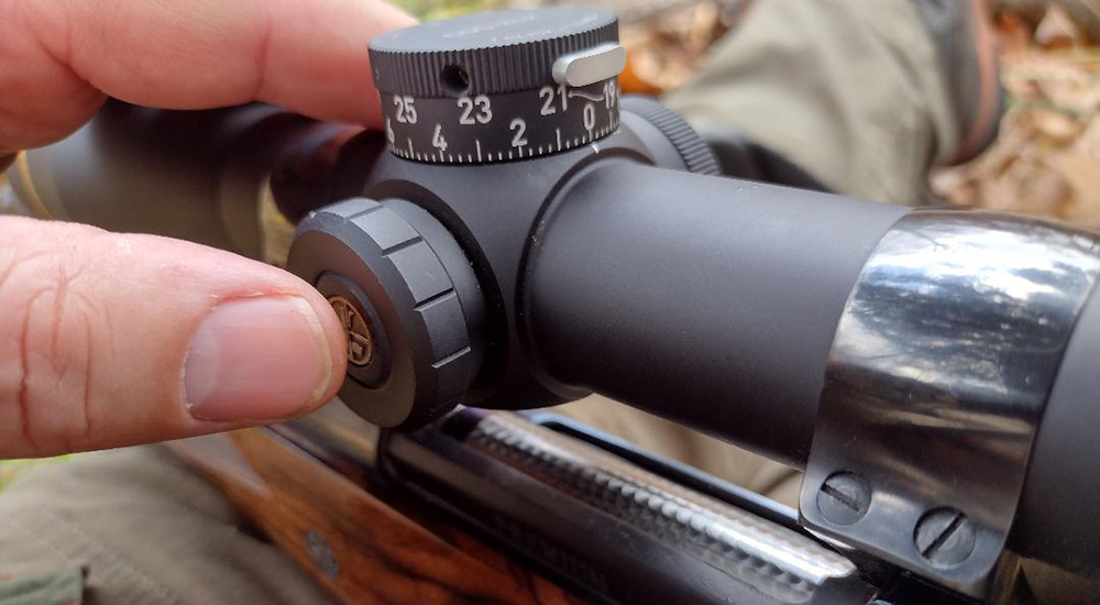 Finger depressed on illumination reticle button on Leupold riflescope.