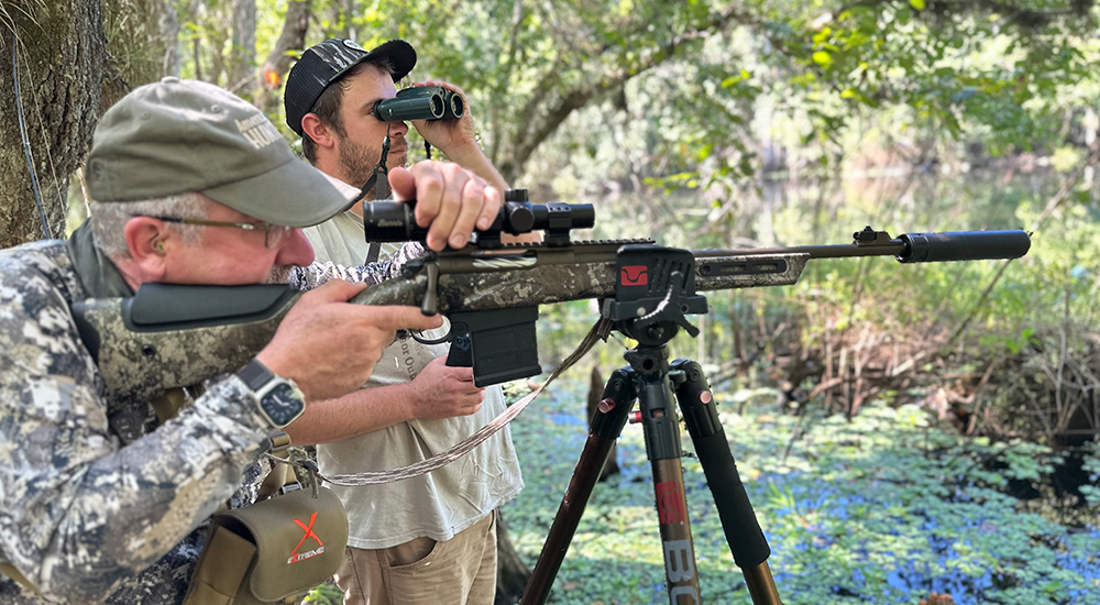 Hunter shooting rifle off of sticks at alligator in Florida.