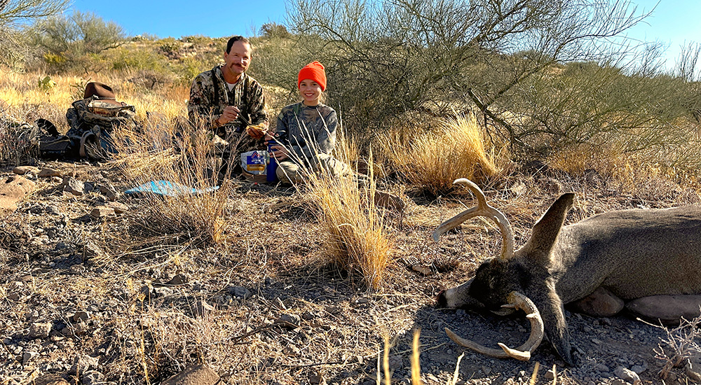 Father and daughter tagging coues deer on mountain.