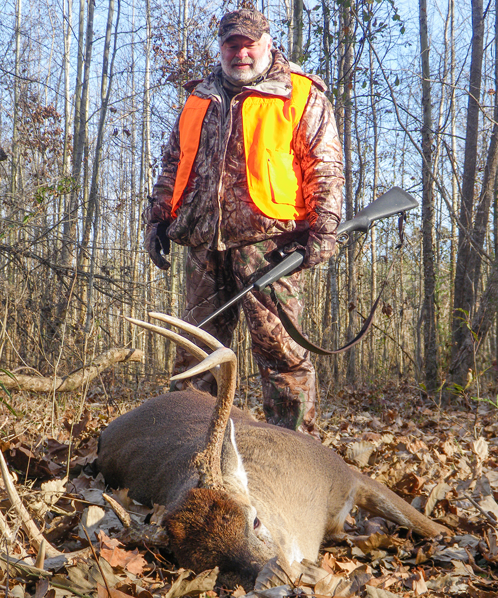 Hunter walking up to white-tailed buck on ground.