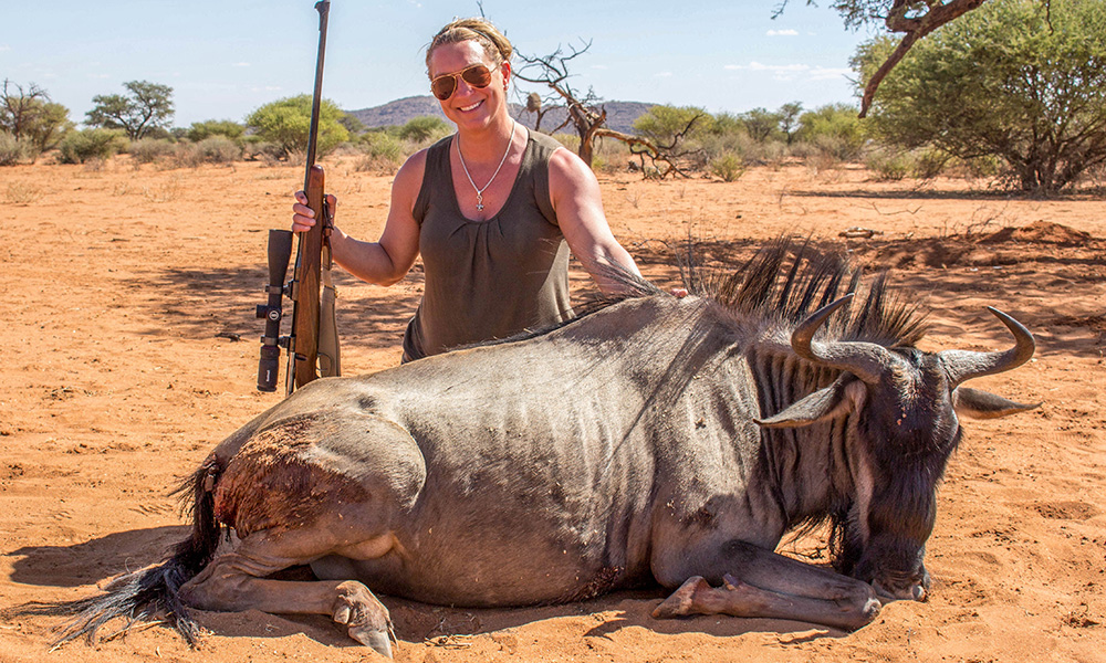 Female hunter posing with blue wildebeest in Africa on safari.