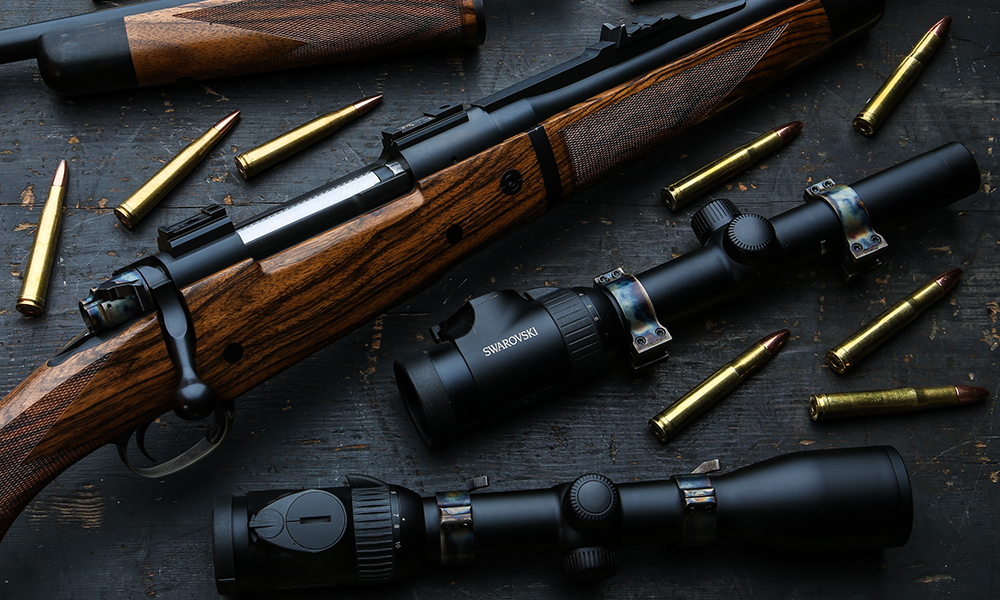 A bolt action rifle with .400 Holland and Holland ammunition and Swarovski scope surrounding on table.