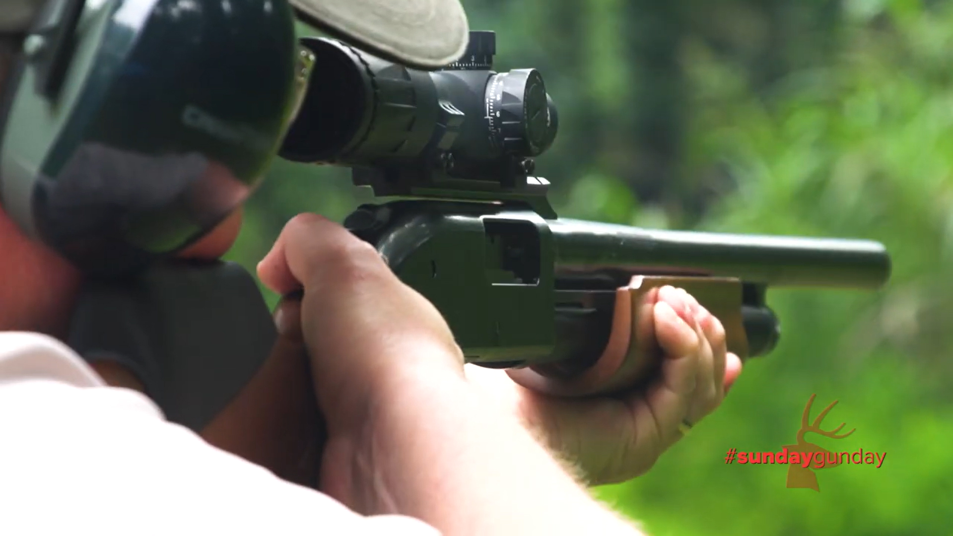 Mossberg 500 Combo Field/Deer pump-action shotgun outdoors rear view in shoulder being fired by an wearing earmuffs and ballcap looking through riflescope on slug barrel