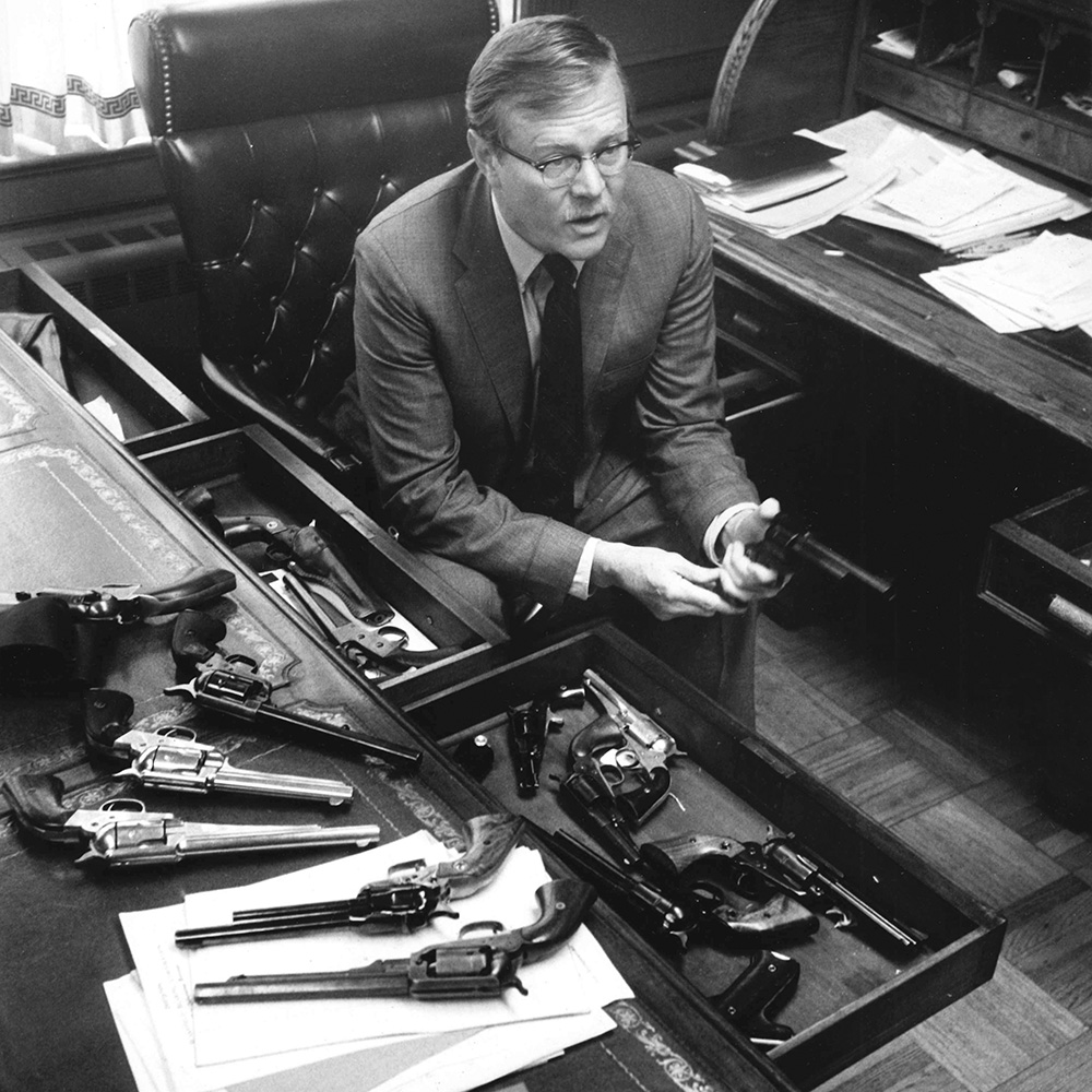 Bill Ruger sitting at desk with multiple revolvers.