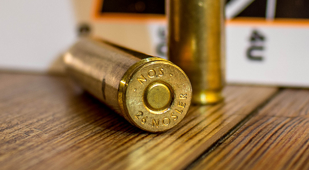 Nosler 26 Nosler ammunition cartridge headstamp on wood table.