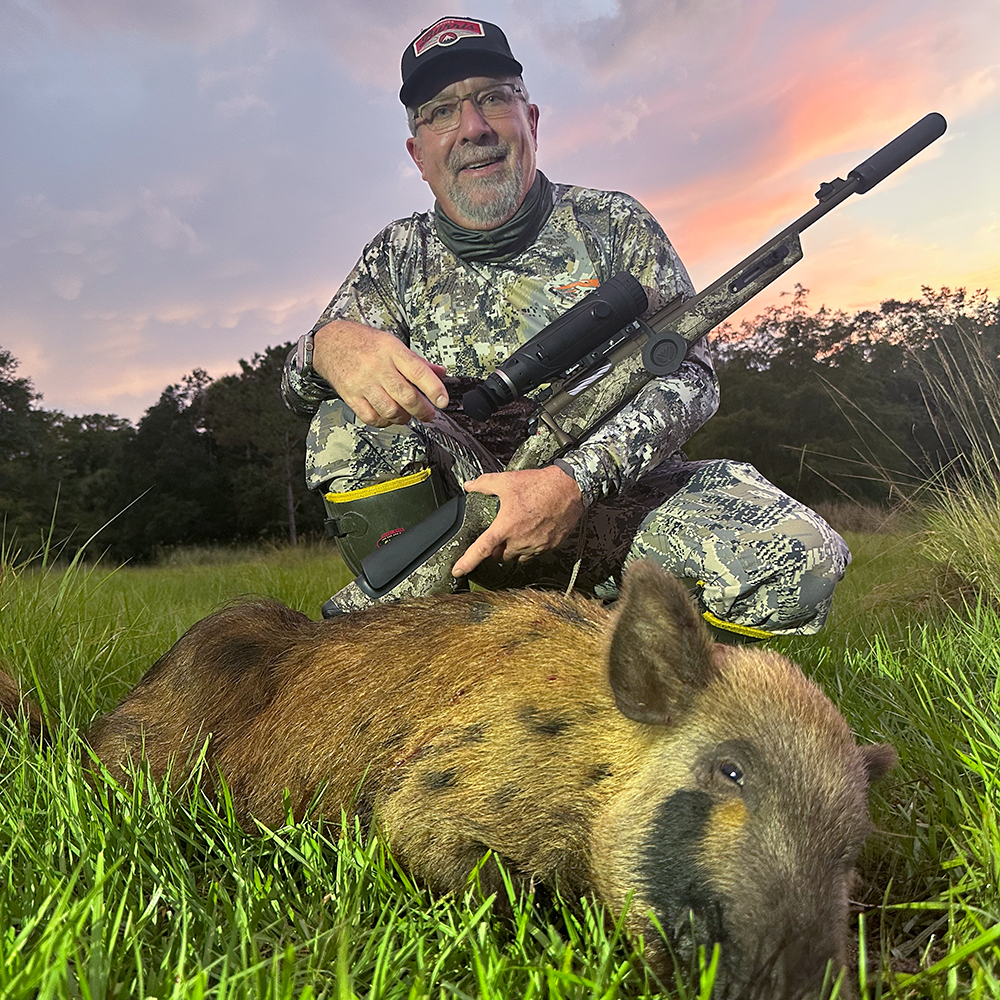 Male hunter with feral hog in Florida field.