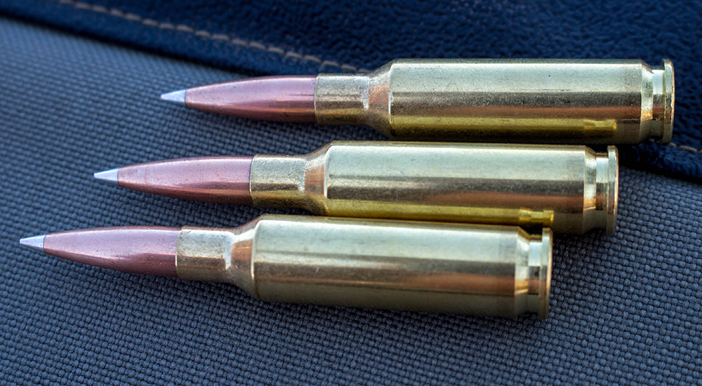 Three 6.5 Creedmoor ammunition cartridges laying sideways facing left.