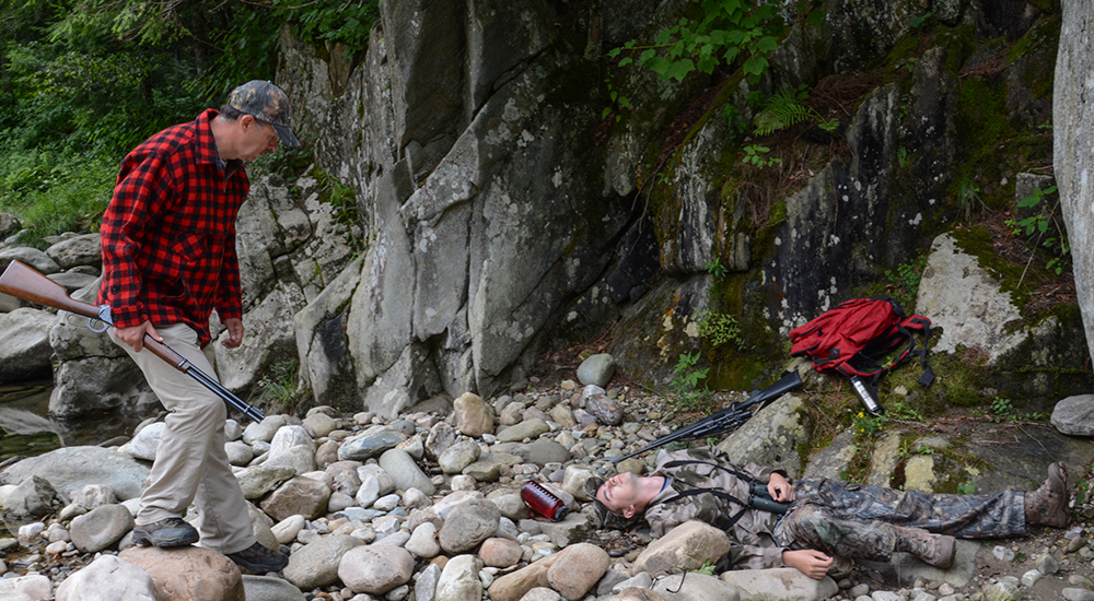 Male hunter walking on rocks near creek.