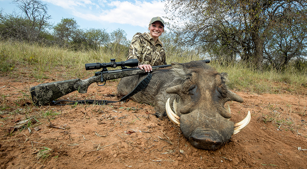 Female hunter with warthog in South Africa.